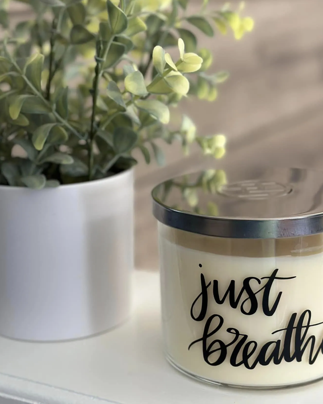 Huntington 3-Wick Just Breathe Candle with Silver Lid, Meditation Silhouette, and Flower Decoration on Wooden Background