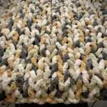 A chunky knit blanket draped over a chair