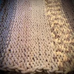 A very large chunky knit blanket in taupe and cream